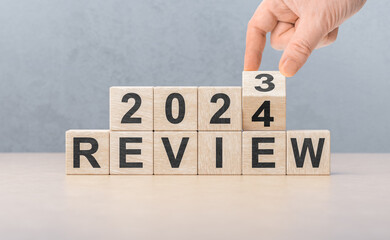 Review 2024. hand flips wooden cube and changes words REVIEW 2023 to REVIEW 2024. New year 2024....