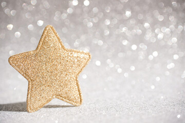 Christmas decor in the form of a gold glittery star on a sparkling gray background. Side view,...