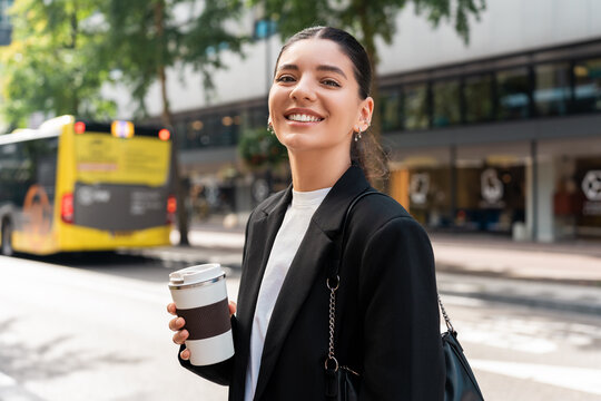 Ready for the day. Cheerful multiracial businesswoman in city street holding a thermo mug