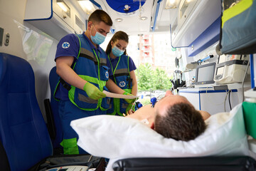 Doctors make a cardiogram to a man in modern ambulance © Svitlana