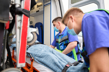 Experienced doctors in uniform unload gurney with patient from ambulance © Svitlana