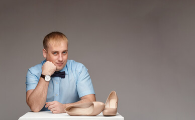 A male shoe seller with glasses holds two different shoes in his hands, showing them to the camera, offering a choice, isolated on white background