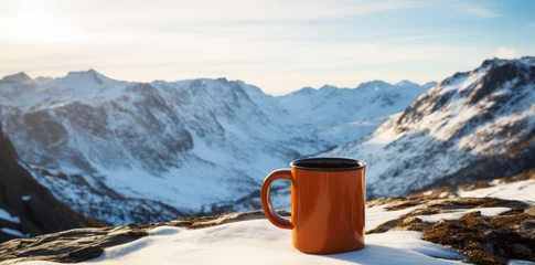 Fototapeten A mug with coffee on a table on a mountain pass against the backdrop of snowy descent from the mountain © GustavsMD