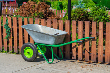 Garden wheelbarrow near decorative fence in the garden
