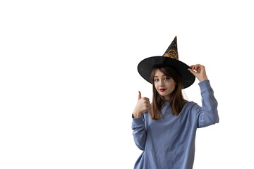 smiling teenage girl in witch hat holding thumb up. fun Halloween concept. isolated photo. copy space,