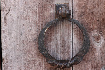 Forged iron handle in the shape of a ring on a wooden door on a shopping mall building in the city...
