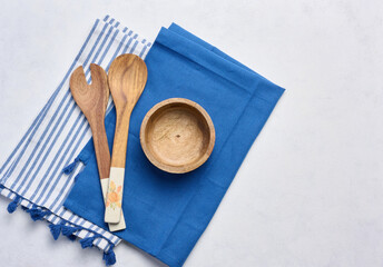 Empty bowl and wooden spoons on a white table, top view