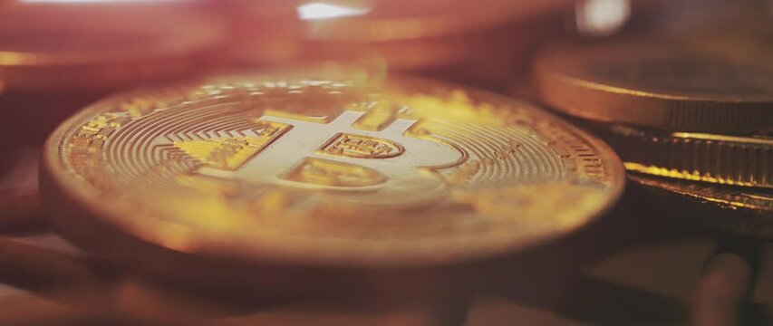 The fire is on the pile of golden bitcoin physical coins. Close-up slow-motion shot