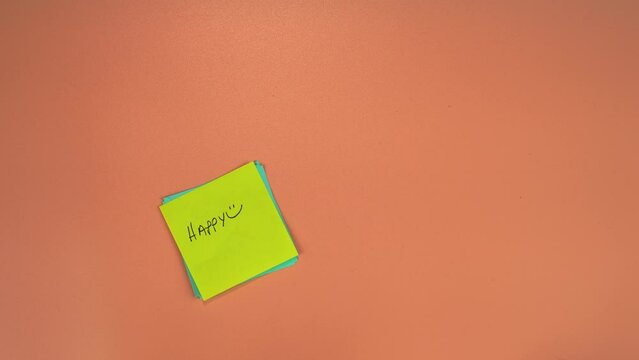 Win-Win and Happy words written on sticky notes. High quality 4k footage of a mans hand placing sticky notes on a pale orange background. Positive outcome concept.