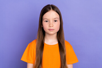 Portrait photo of serious small cute face schoolgirl wearing orange casual t shirt preschool age isolated on pastel violet color background