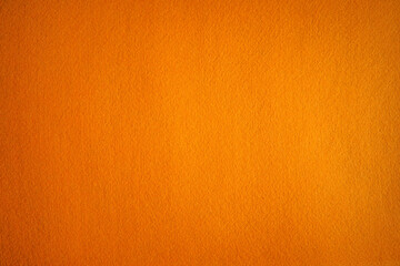 Photo of an orange background texture made of felt fabric. Soft textiles of red color.