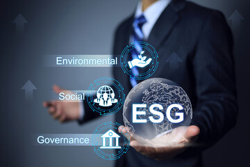 ESG environmental social governance concept. Businessman holding globe to apply less emissions into...