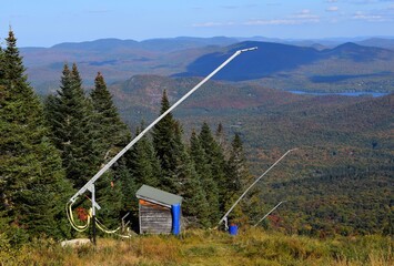 view from top of Mont-Tremblant passed snow guns towards the Laurentian mountains with lake Superior in the background, 