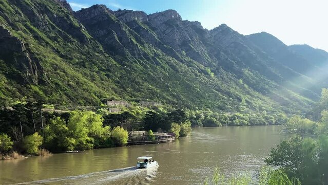 Scenic view of passenger boat crosses river on mountain range background