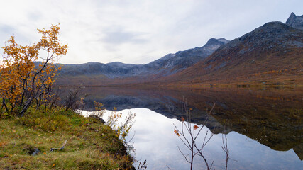 steile Berge auf der Insel Kvaløya, die sich im Wasser des Bergsee spiegeln, in Troms, Norwegen....