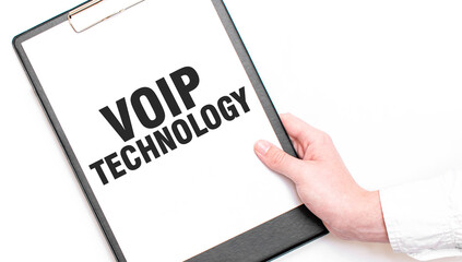 A businessman holds a folder with paper sheet with the text VOIP TECHNOLOGY. Business concept.