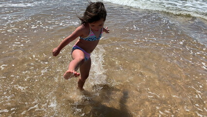 Fototapeta premium Little girl child playing at beach, kid running at sea shore