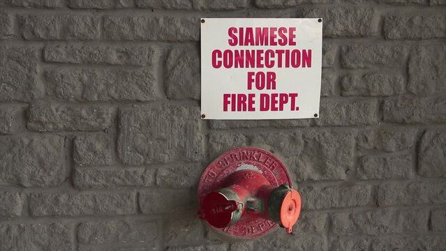 siamese connection for fire dept department writing caption text square white red sign on brick wall above siamese twin connections