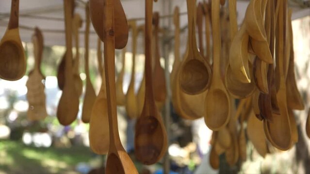 dolly close up shot of a lot of wooden spoons hanging in the shed, in the craft market