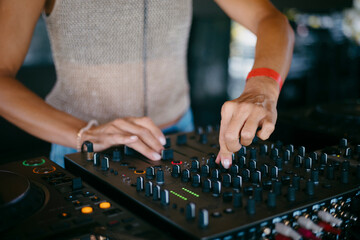 woman DJ Hands creating and regulating music on dj console mixer in a music festival