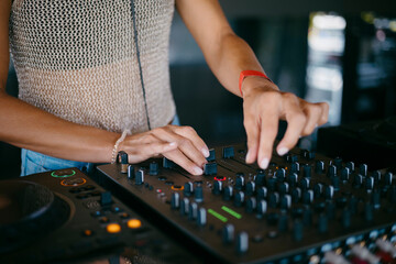 woman DJ Hands creating and regulating music on dj console mixer in a music festival