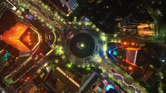 Aerial View of traffic on roundabout around Selamat Datang monument, Multi lane highway in large urban city center Cityscape of high rise buildings in Jakarta, Indonesia at night