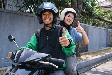 Happy commercial motorcycle taxi driver and passenger showing thumbs up