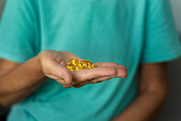 handful of yellow pills in adult hands. Women's vitamins, men's vitamins. Taking care of health, supporting immunity. Vitamins after illness