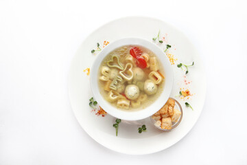 Children's menu. Soup with chicken meatballs and vermicelli. Crackers with soup.Flat lay. Top view. Copy space. Isolated object.