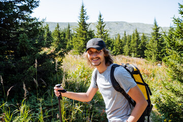 The guy walks along a mountain path, walks in the national park, taiga forest, hiking in the mountains alone, fun adventures, outdoor recreation, an active lifestyle.