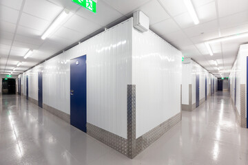Hallway with blue doors storage units. Concrete floor - Powered by Adobe