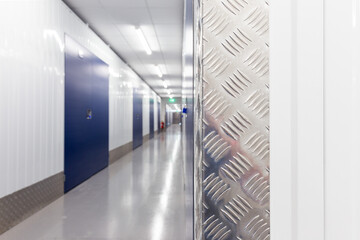 Hallway with blue doors storage units. Concrete floor