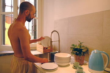 Contemporary Living, young man 30-35 years old washing dishes in modern kitchen, concept Sharing...