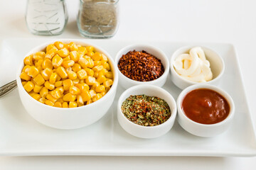Natural, freshly boiled corn grains with various spices designed on a white plate