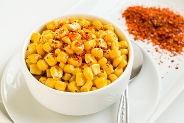 Natural boiled sweet corn with hot red pepper in a white bowl