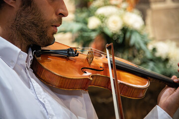 Caucasian violinist man wearing classical clothes and performing in a closed space, church. Live...