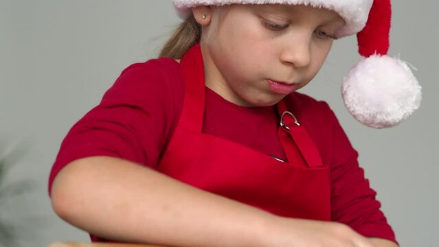A child bakes Christmas cookies. Portrait of a girl in a stanta costume. Children bake Christmas cookies. A family with children celebrates Christmas at home. A little girl is cooking in the kitchen.