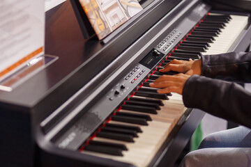 A musician's hands test a piano at an exhibition of musical instruments