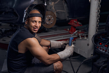 Auto-mechanic smiling finishing weld the car earlier that he thought