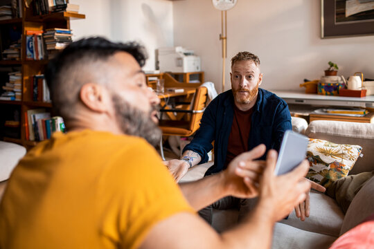 Young male gay couple arguing about alleged text messages from a another person at home
