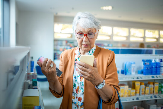 Senior woman making sure she got the right medication on her smartphone at a pharmacy