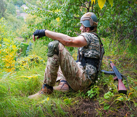 A soldier sits in the grass and looks into the distance