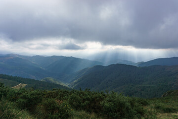 Basque landscape beautiful hills covered with forest and sun rays breaking through clouds on autumn day, Aiako Harria, Gipuzkoa, Basque Country, Spain
