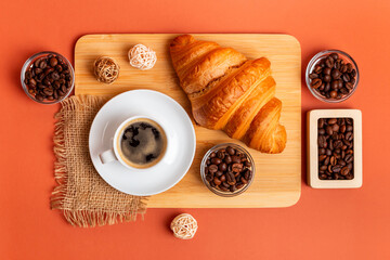 French croissant, cup of black coffee, aromatic roasted arabica and robusta coffee beans in wooden...