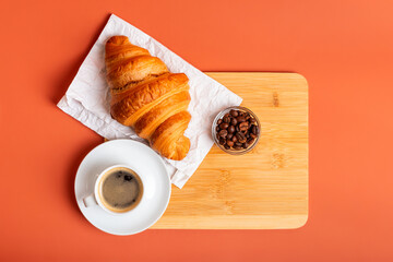 French croissant, cup of black coffee, aromatic roasted arabica and robusta coffee beans in a glass...