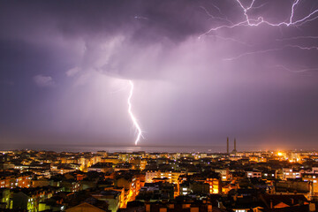 Lightning strikes over the city at night.
