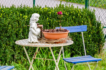 Sculpture, gardening tools and flowers in garden