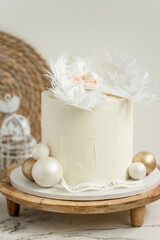 Christening cake with white cream cheese frosting decorated with mastic newborn baby sleeping on the edible angel wings. Little baby angel sleeping. Baby born celebration.
