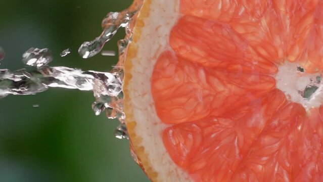 Super slow motion shot of sliced grapefruit slice with splashes of water flying in air on black background. Freshness and refreshing invigorating citrus sough. Lemonade or juice Slow motion. droplets.