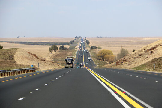The N3 freeway from Johannesburg to Durban in South Africa, straight road to the horizon over dry landscape with cars and trucks from drivers point of view